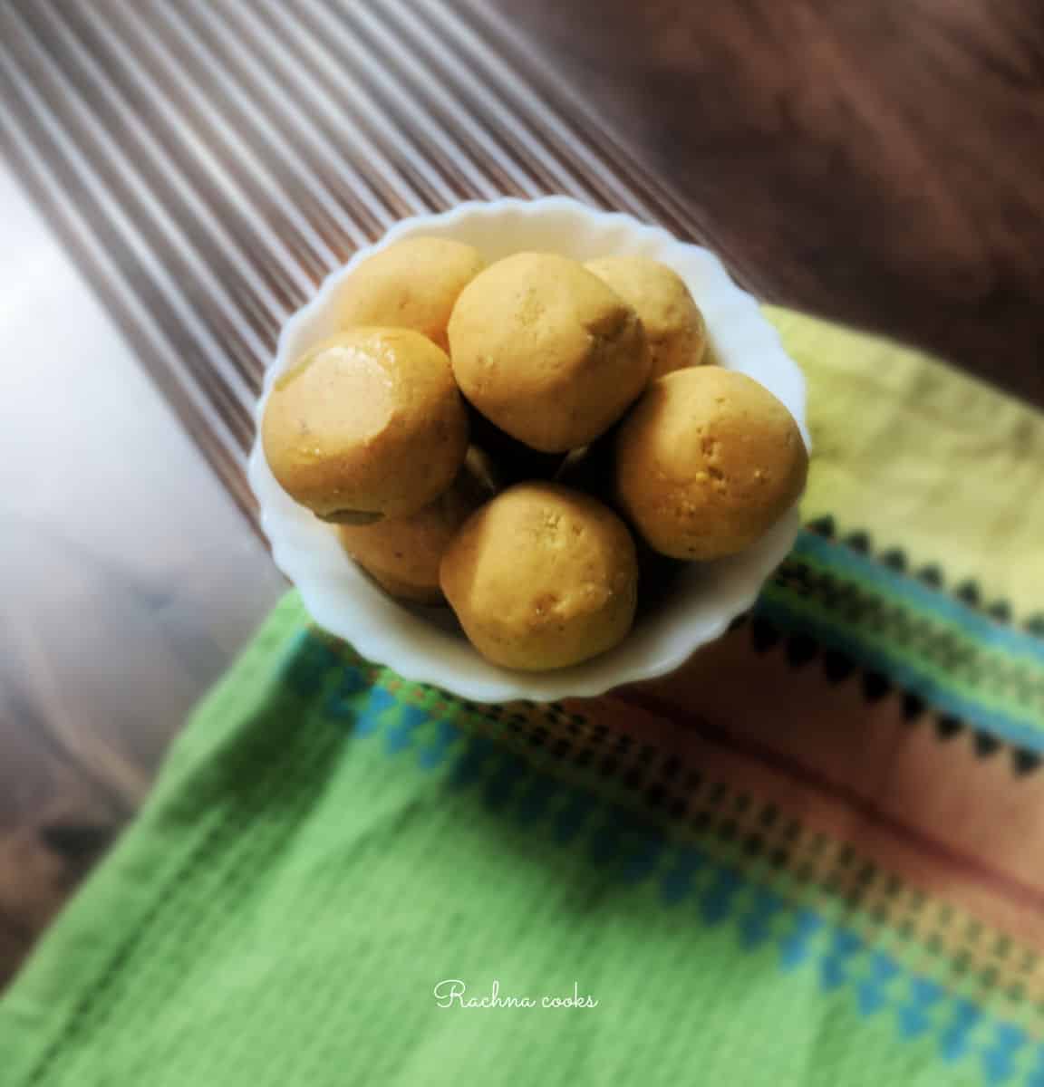 beautiful besan ladoos in a white bowl on a brown background