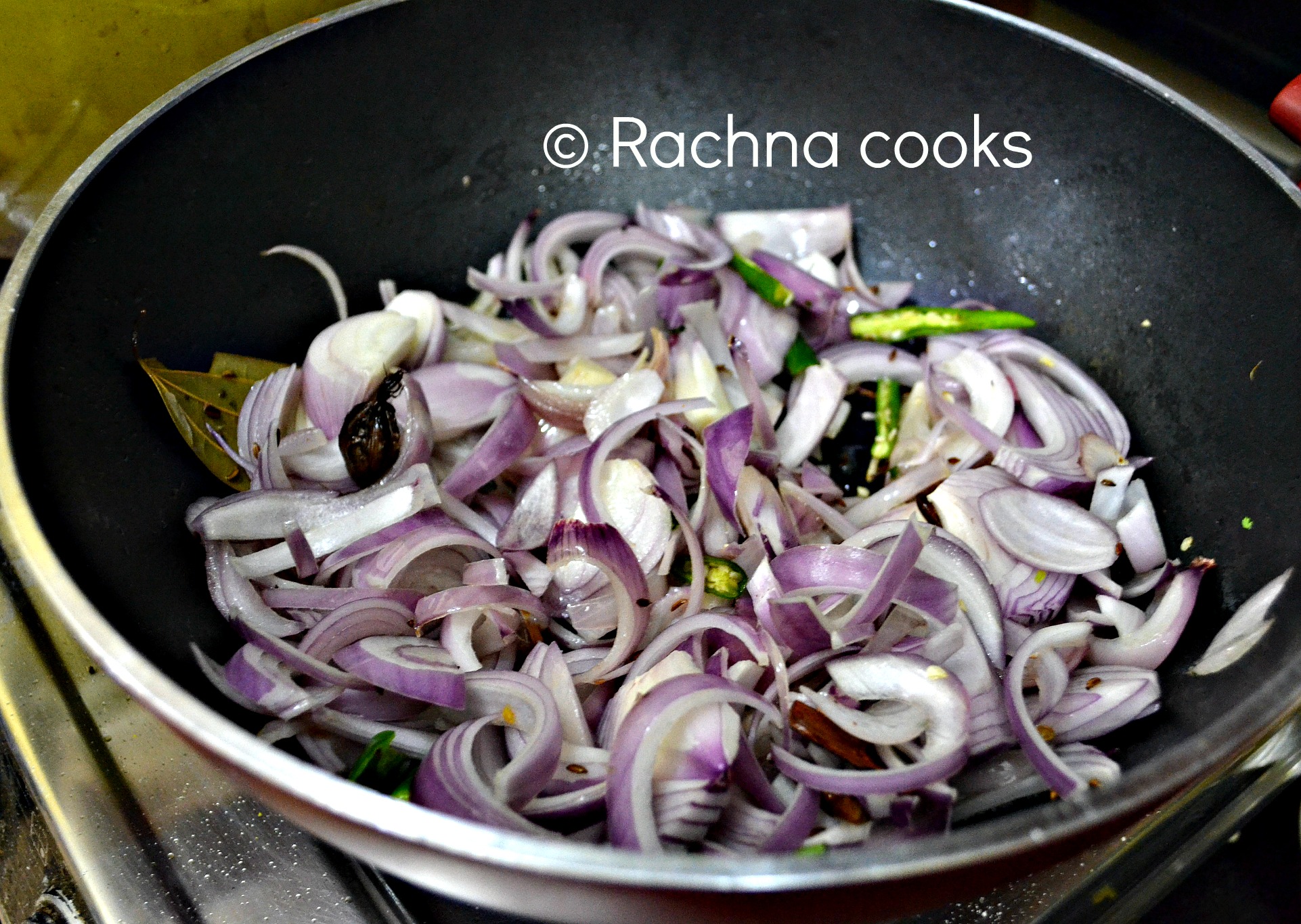 Sauteing sliced onions and green chillies in a kadhai or work