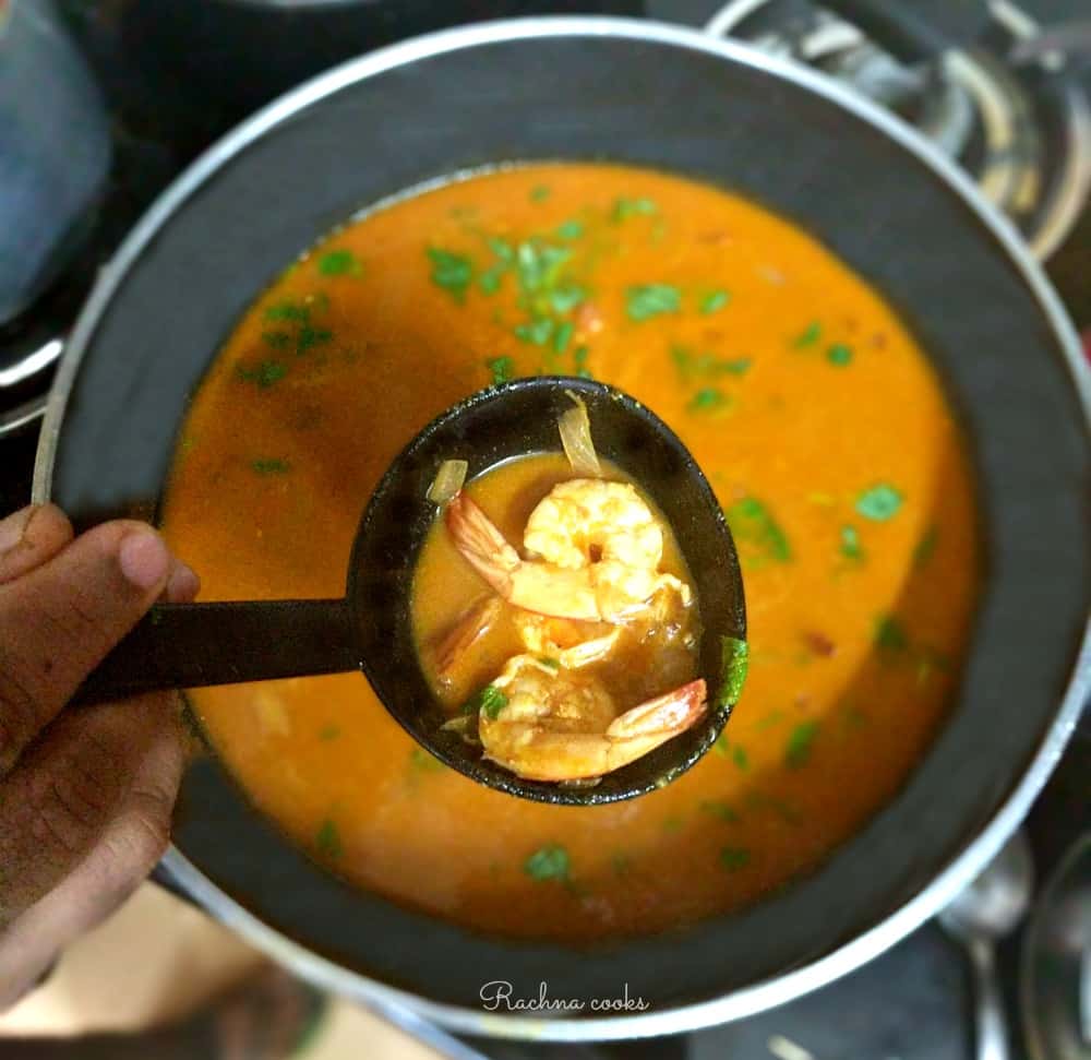 A ladle of Goan shrimp curry held up in focus