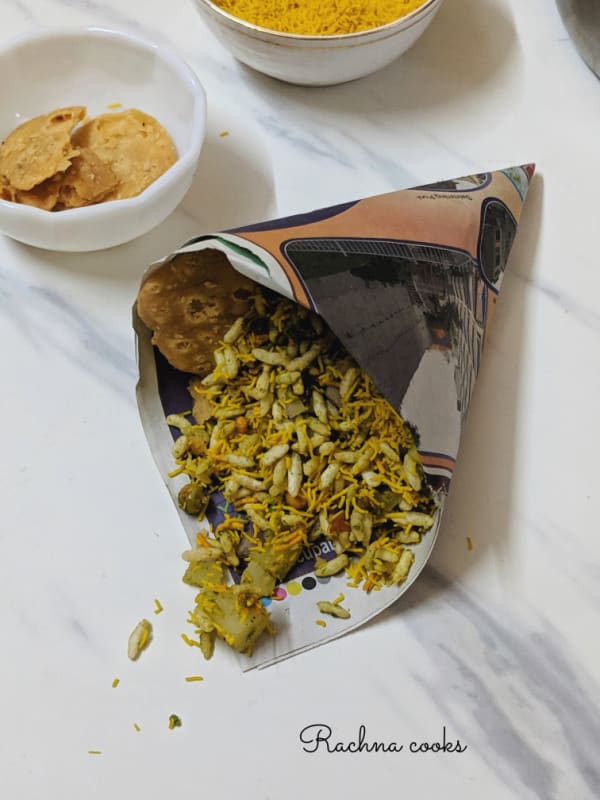 Indian street food bhel puri in a paper cone on a white background.