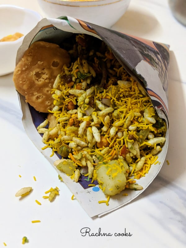 Indian street food bhel puri in a paper cone on a white background.