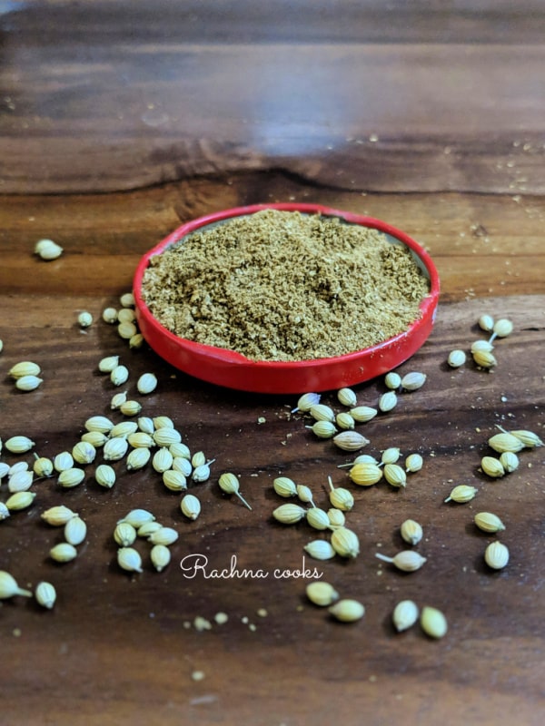 Ground coriander in a red tinged shallow dish with few scattered coriander seeds