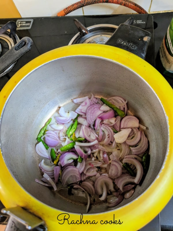Sliced onions and green chillies frying in a pressure cooker