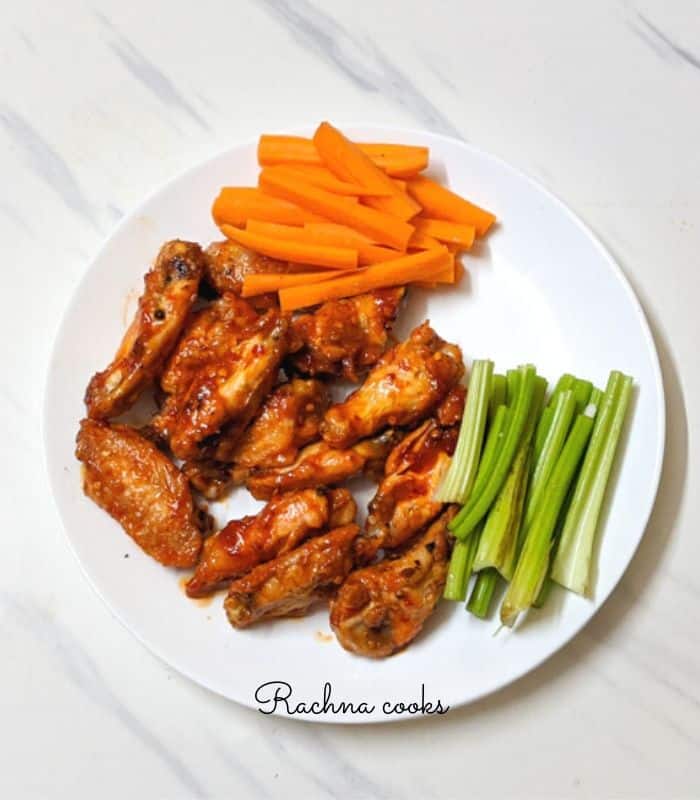 a plate full of delightful buffalo chicken wings air fried served with carrot batons and celery sticks