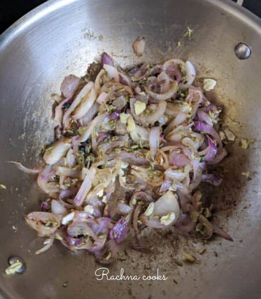 Browning sliced onion and ginger garlic paste in a wok
